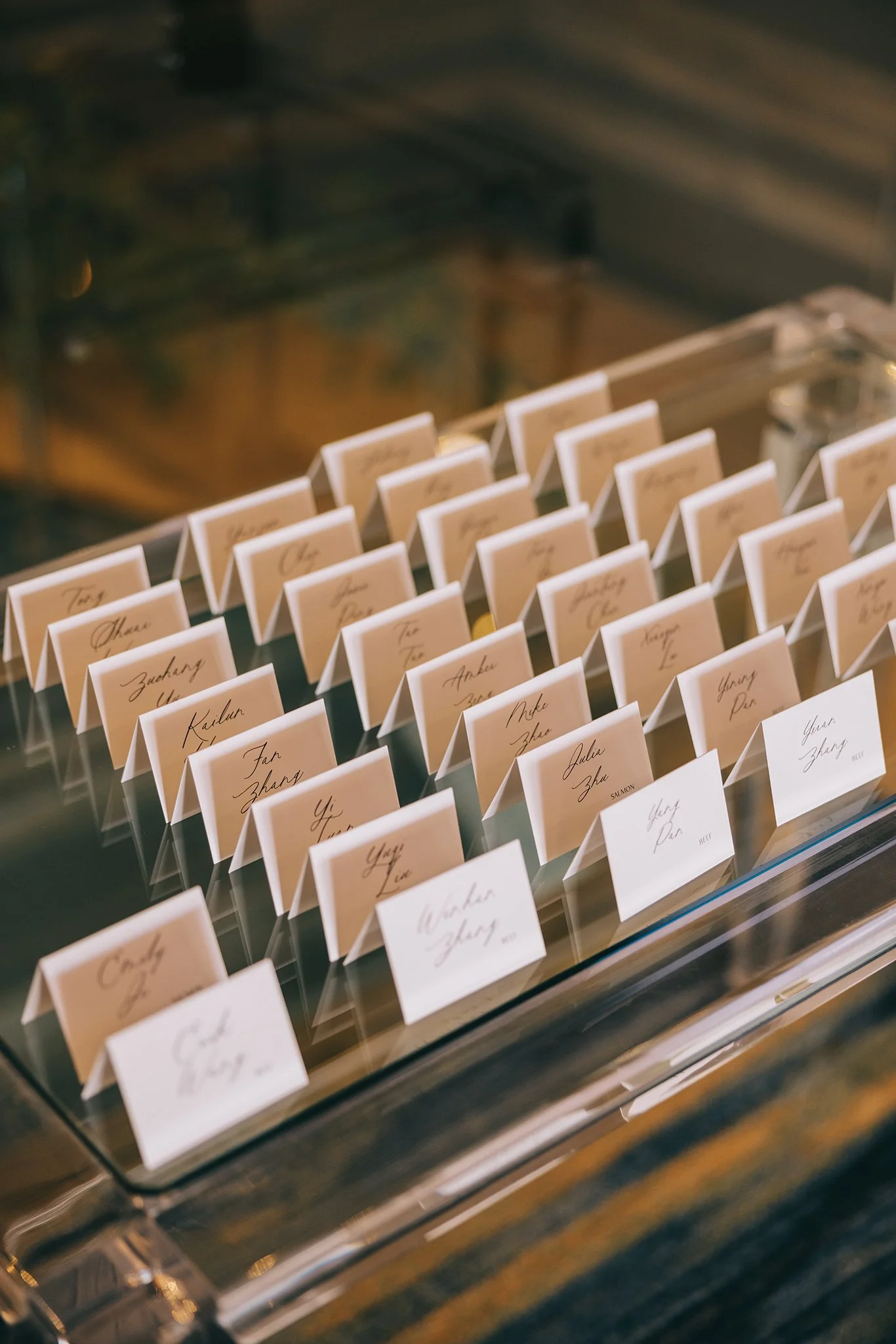 Place cards arranged on a table, each with handwritten names and table assignments for an event.