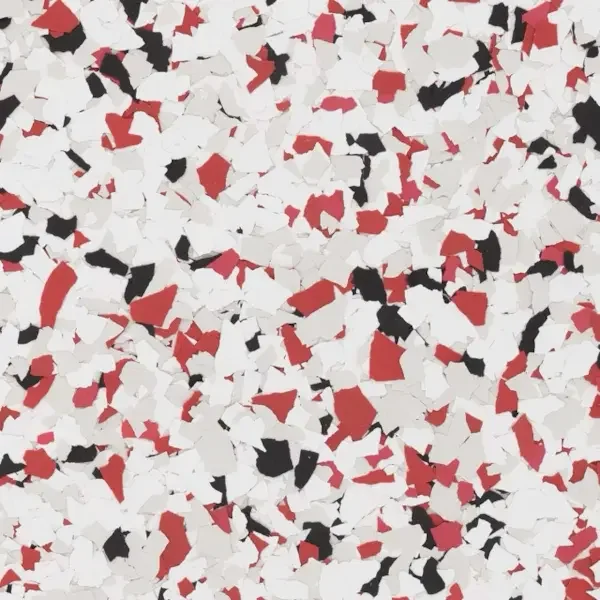 Close-up of red, black, and white epoxy floor flakes scattered on a surface.
