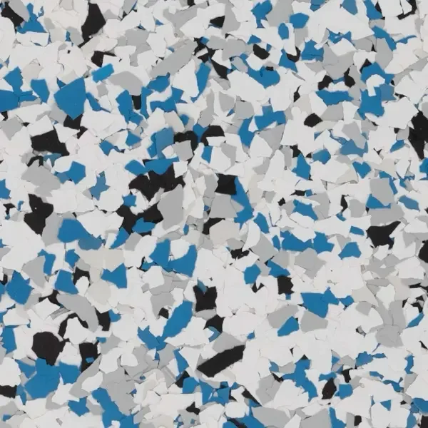 Close-up of multicolored epoxy floor flake, primarily white, with some black, blue, and gray pieces scattered throughout.
