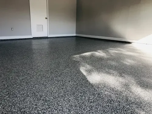 Empty room with grey carpet, white walls, closed door, and sunlight streaming through window.