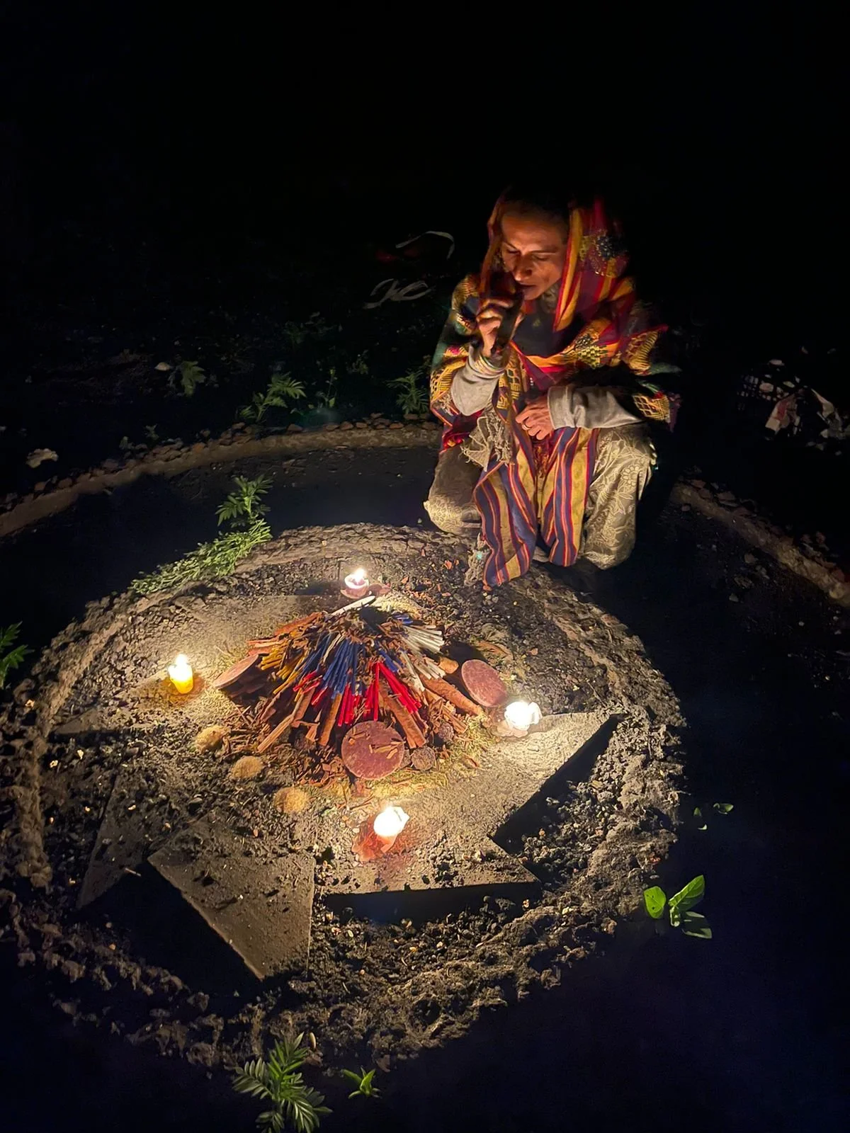 Woman sitting by a ceremonial fire with ayahuasca tools at a veteran-led retreat focused on connection, healing, and personal transformation