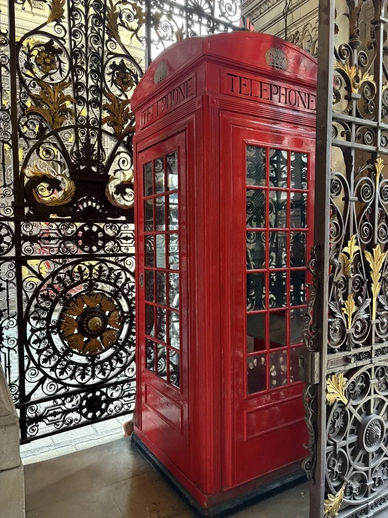 Photo of a red telephone box in London next to an ornate gate