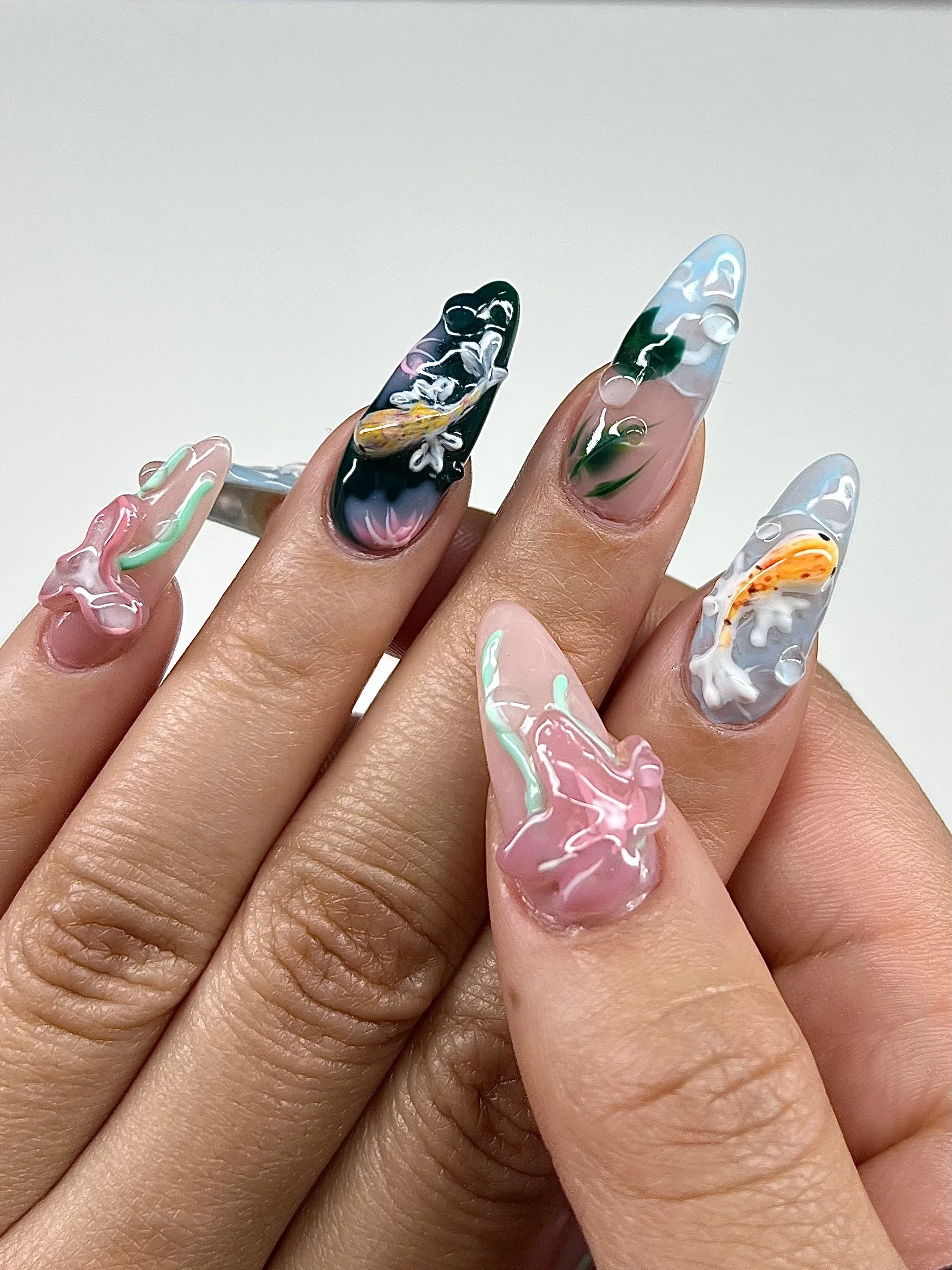 Close-up of a hand with decorated long acrylic nails featuring various designs and colors.