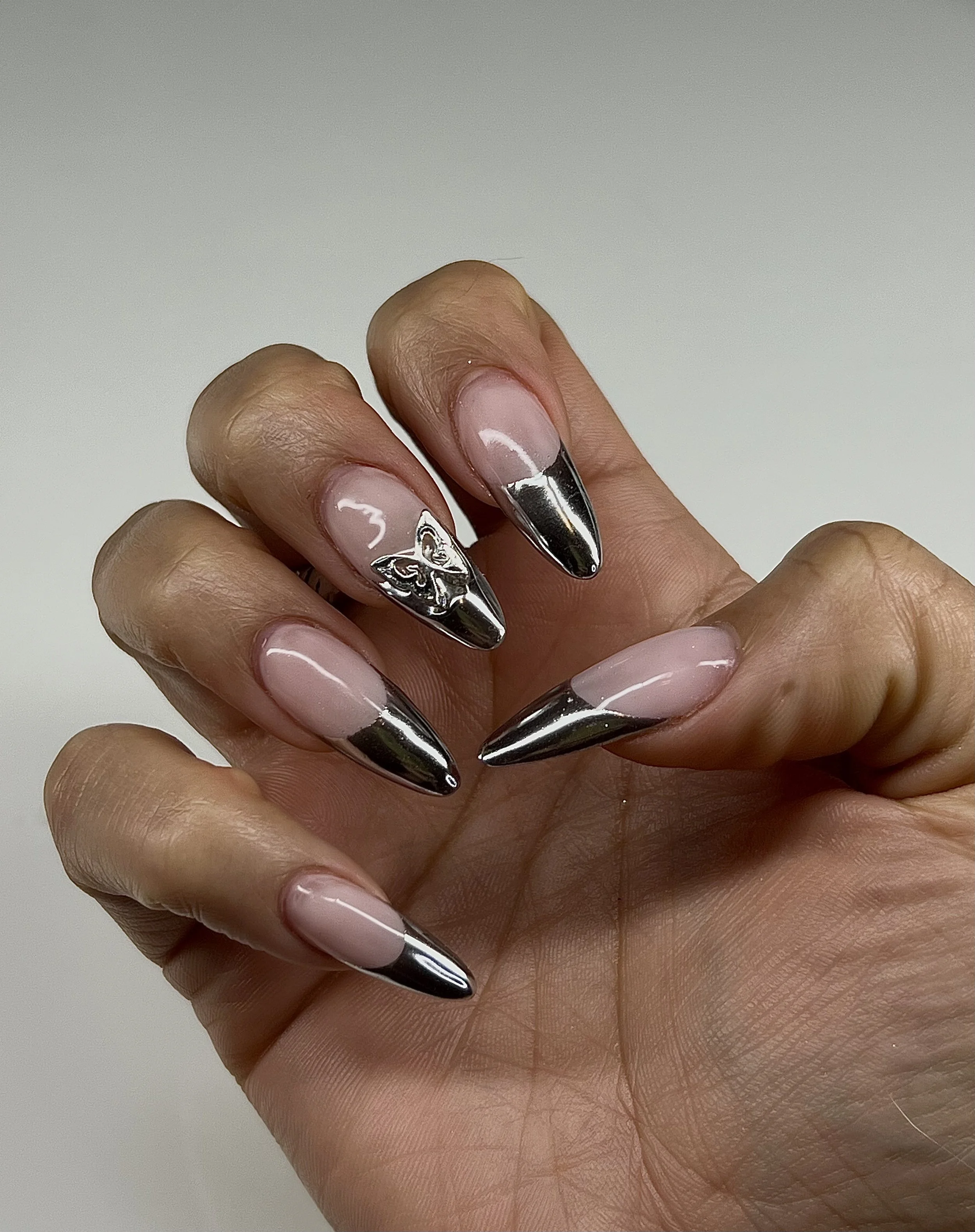 Close-up of a hand with long, decorated acrylic nails standing against a white background.