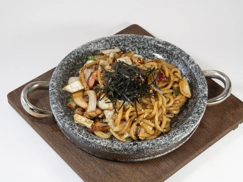 A bowl of Asian-style stir-fried noodles with vegetables and seaweed on top