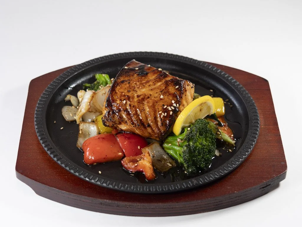 Grilled salmon with vegetables on a black skillet