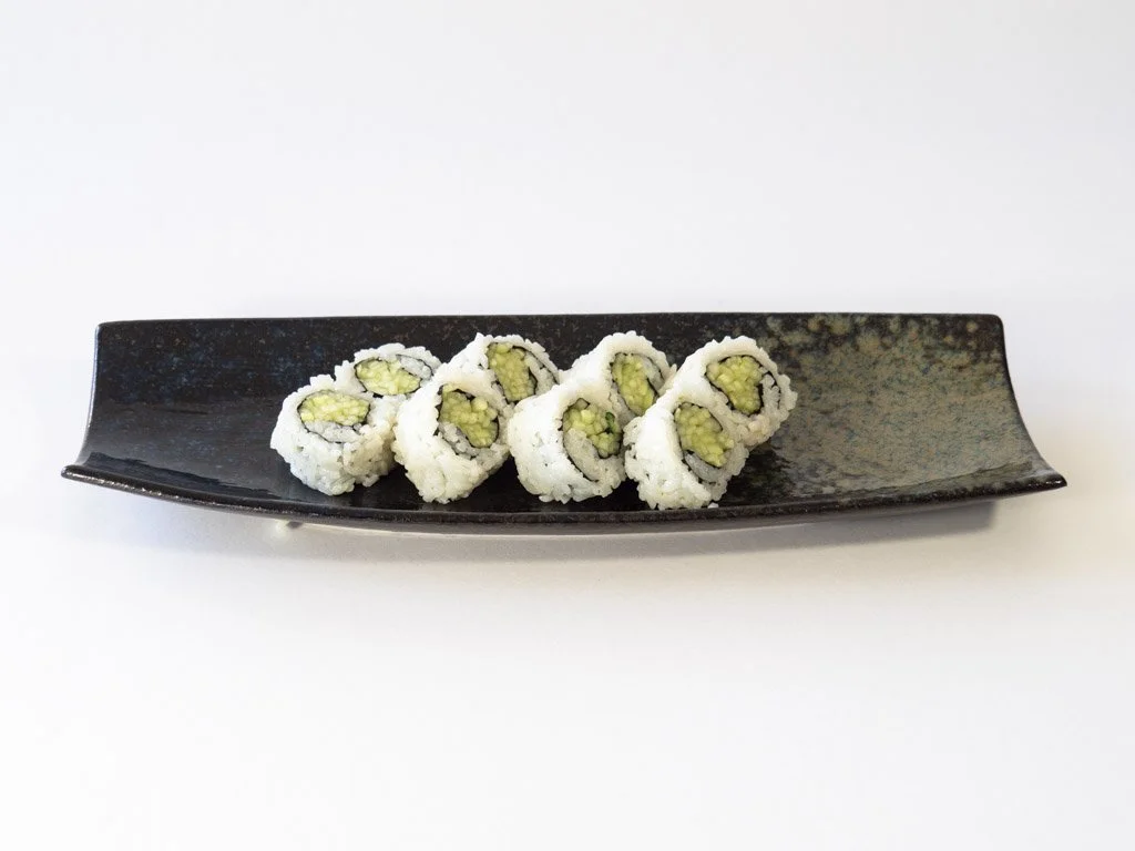 Sushi rolls on a black rectangular plate with white background.