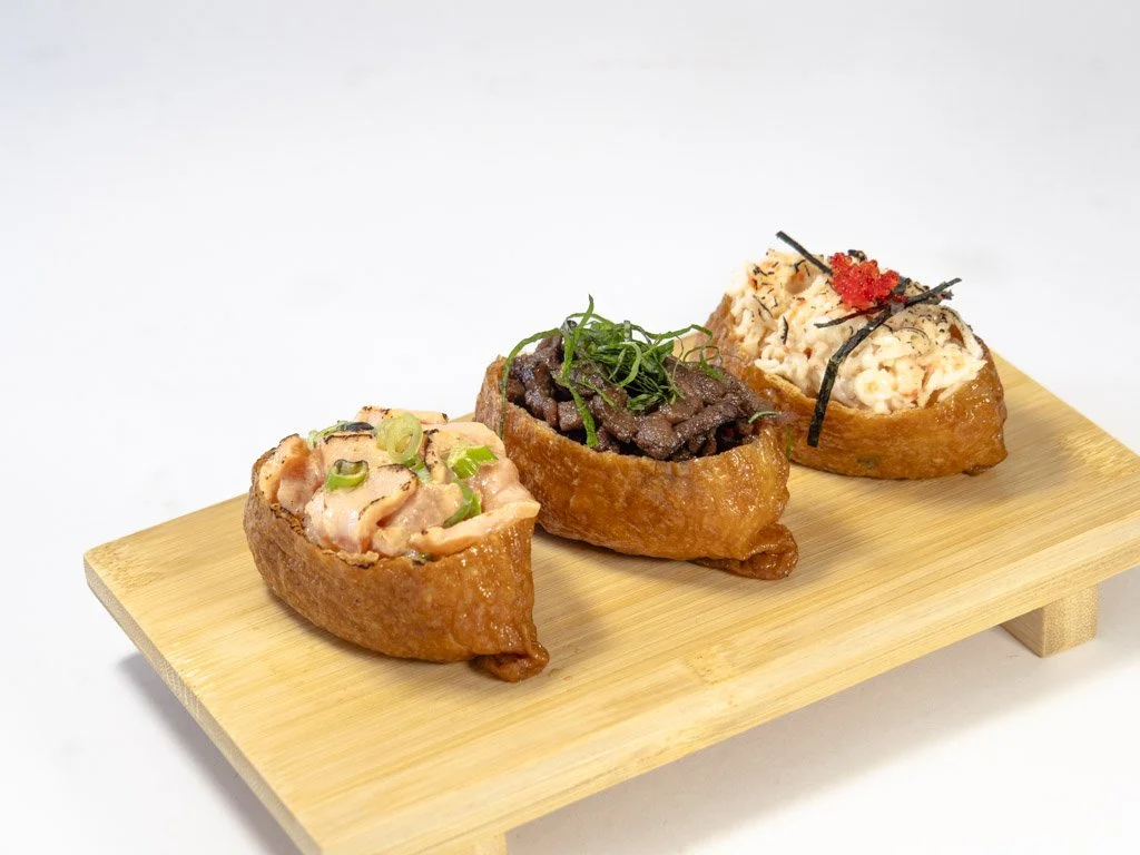 Three pieces of Japanese sushi on a wooden board with various toppings.