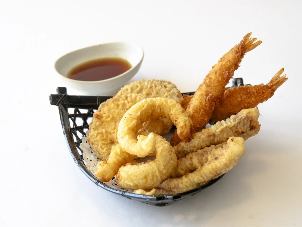 Basket of assorted fried seafood including shrimp, calamari, and fish fillets with dipping sauce