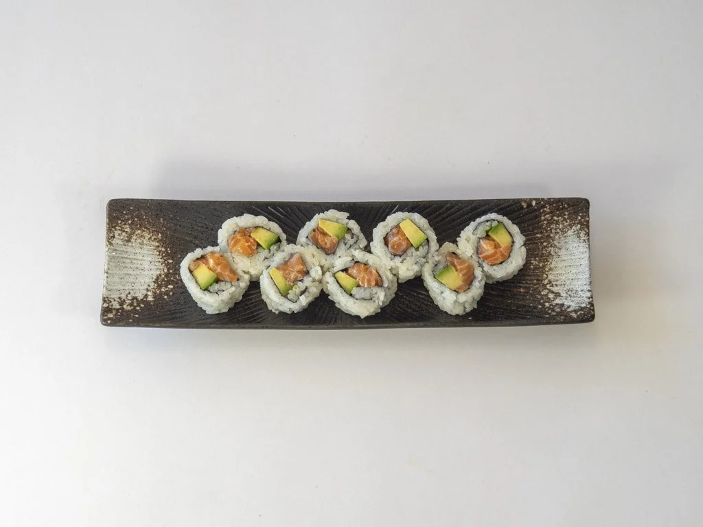 Sushi rolls with salmon and avocado on a rectangular black plate