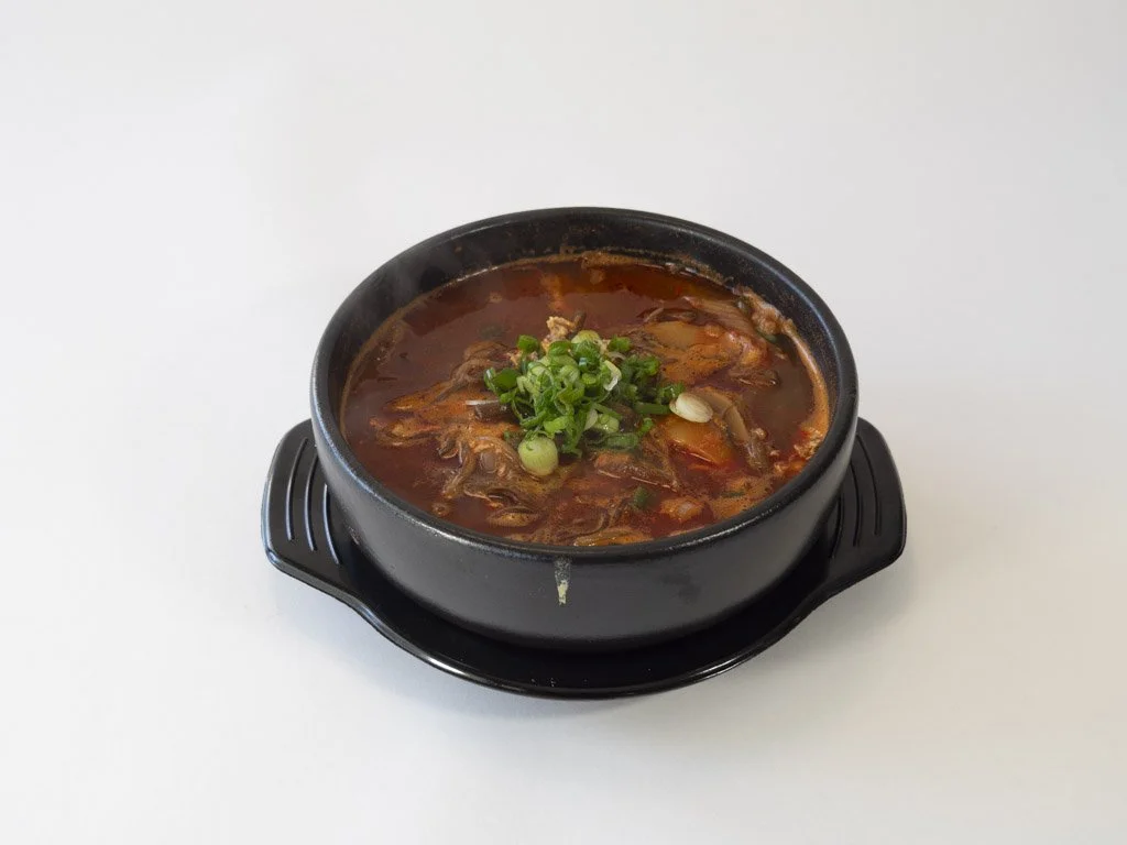 A bowl of hot spicy Korean soup garnished with chopped green onions.