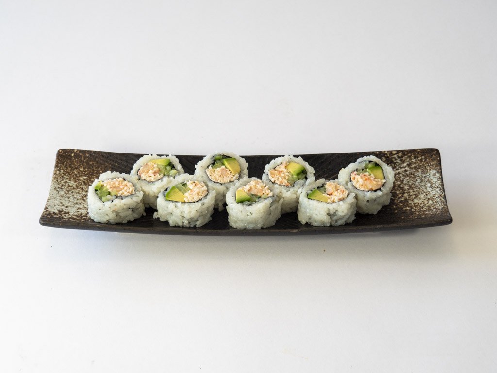 Eight pieces of sushi with rice, cucumber, and seafood filling on a dark rectangular plate