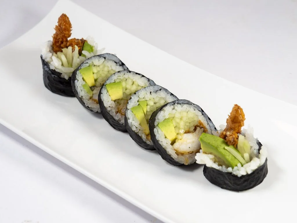 A plate of assorted sushi rolls, including shrimp tempura, avocado, cucumber, wrapped in seaweed and rice.