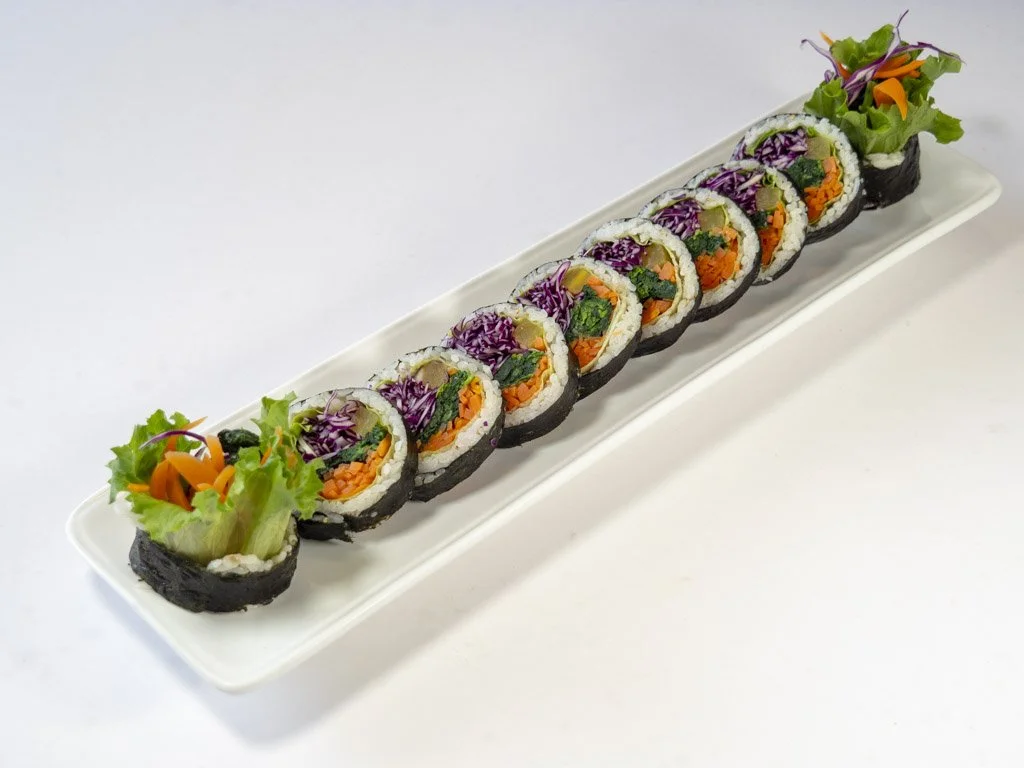 Sushi rolls with colorful vegetables on a long white plate