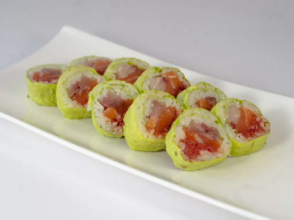 Sushi rolls with rice, raw salmon, and avocado, served on a white rectangular plate.