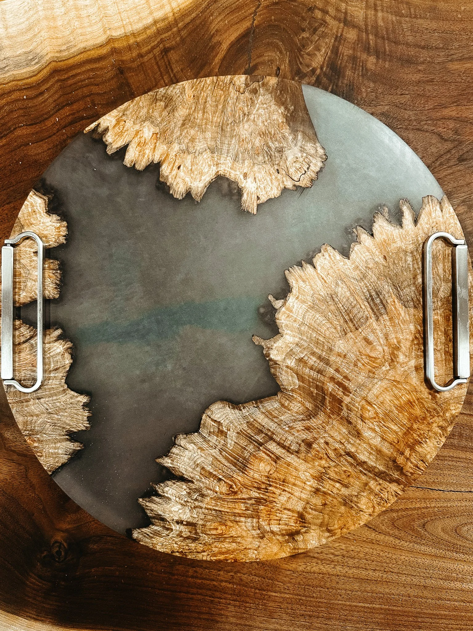 A decorative circular wooden tray with intricate wood grain patterns, placed on a wooden surface.