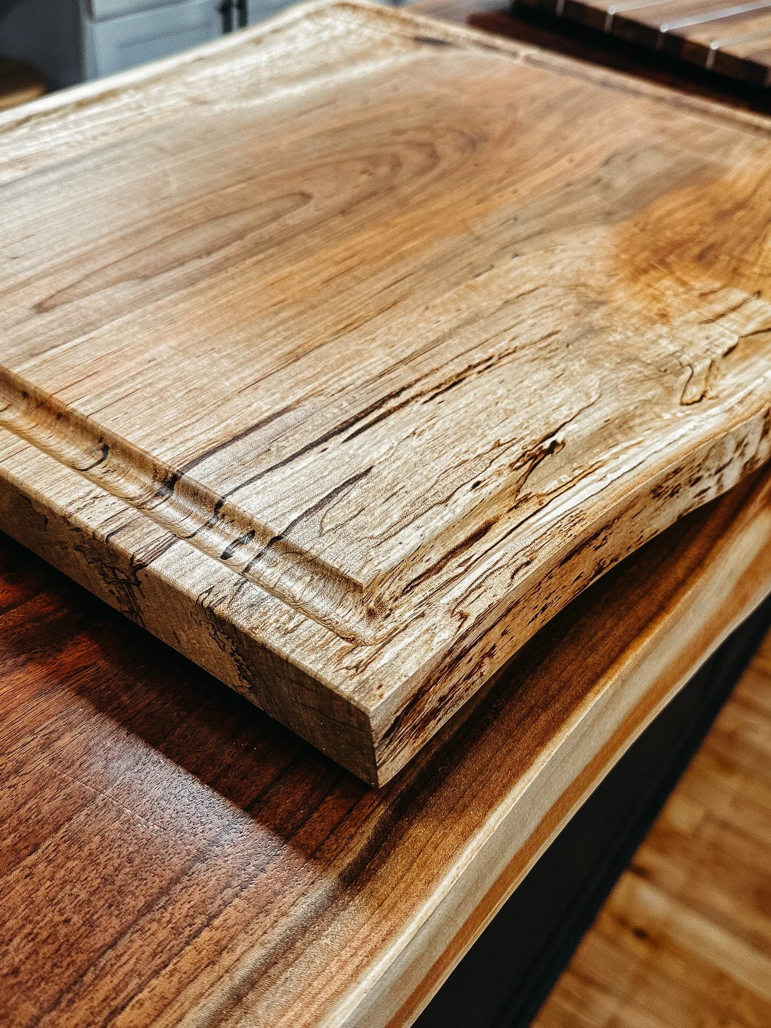 Close-up of a wooden cutting board with a natural finish, showing wood grain and imperfections.