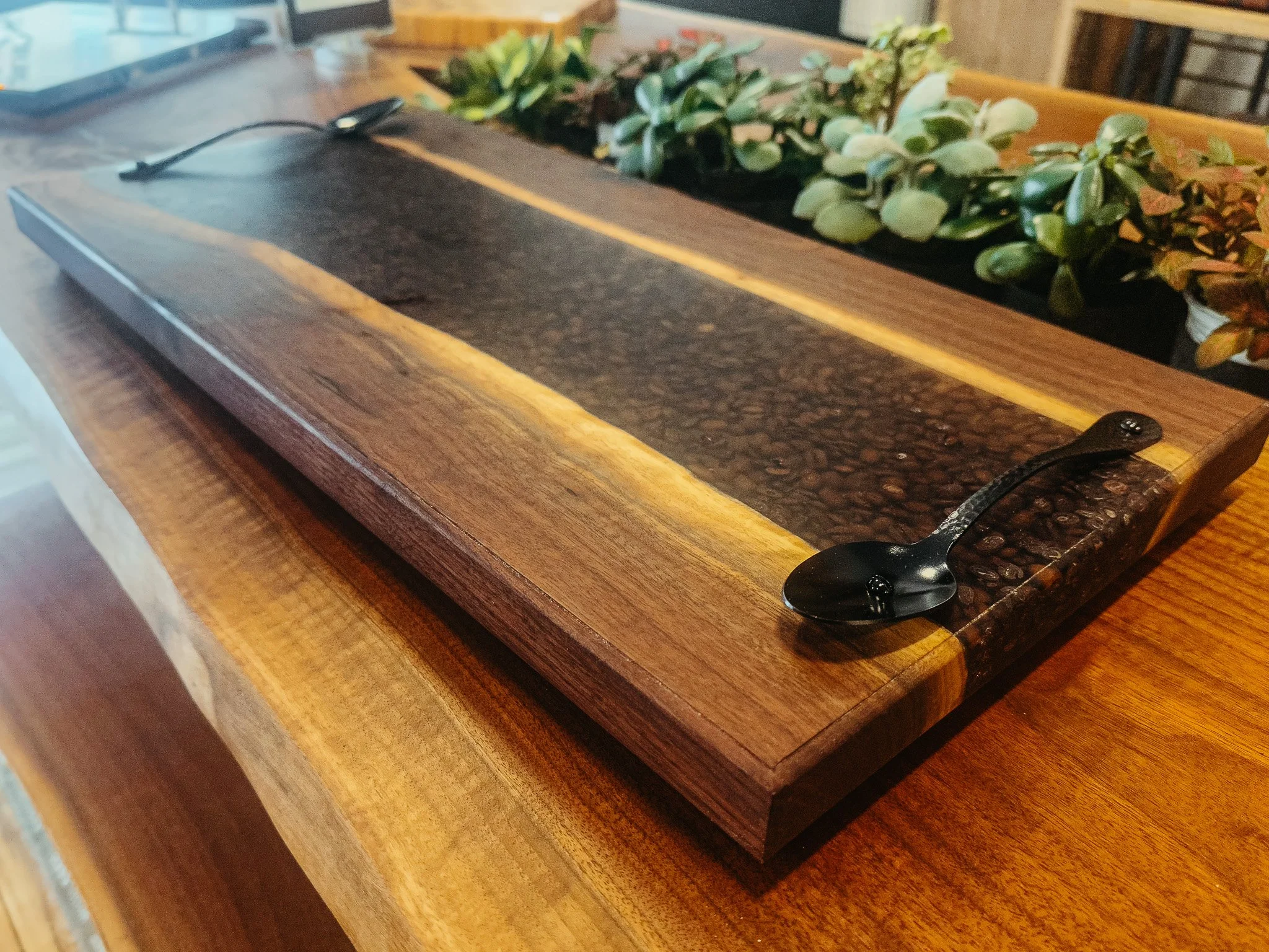 A rectangular wooden planter with green plants, placed on a wooden table.