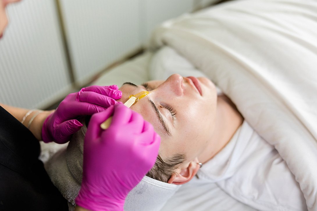 A man having wax put between his brows for hair removal in Bend, Oregon.