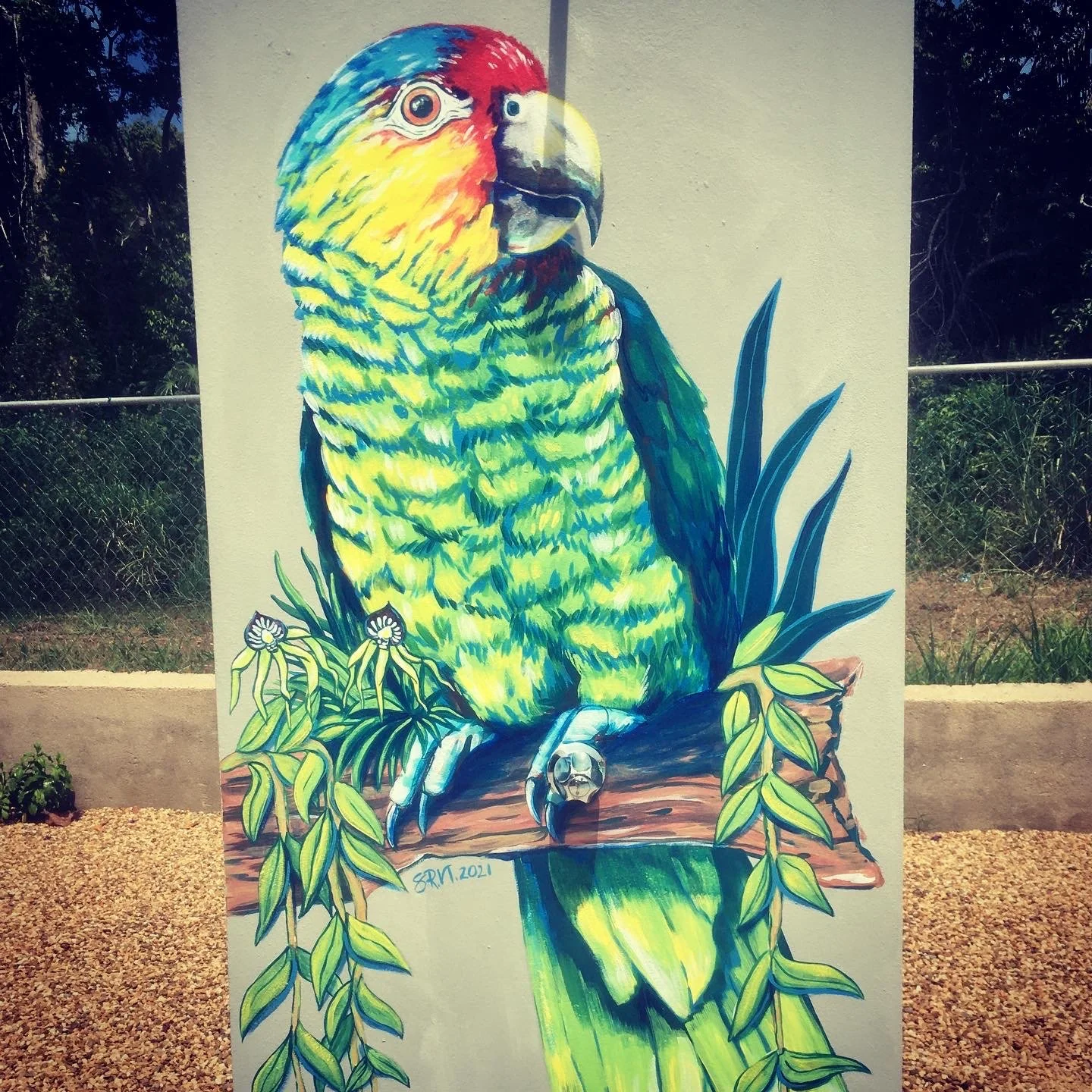 Colorful mural of a parrot perched on a branch, surrounded by green leaves and plants, with a blank beige background.