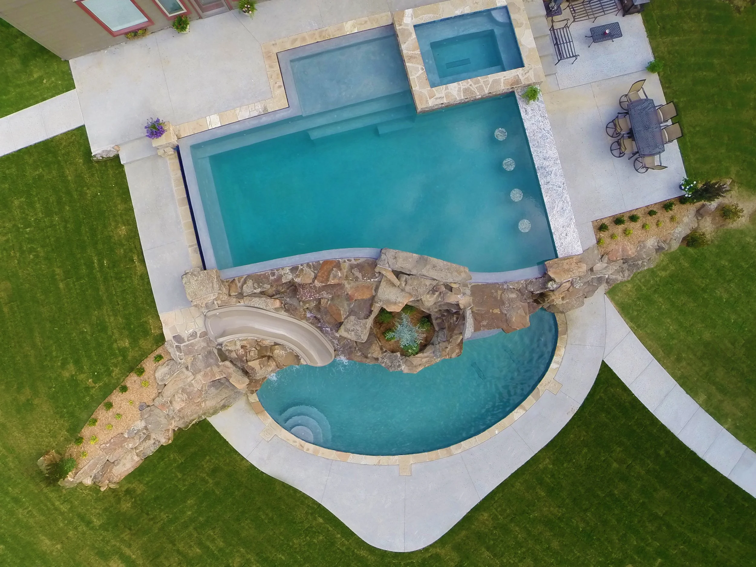This custom resort-style pool project was designed as a complete backyard destination, combining luxury entertaining spaces with family-friendly features. The upper adult pool includes a vanishing edge and perimeter overflow detail, creating a clean,
