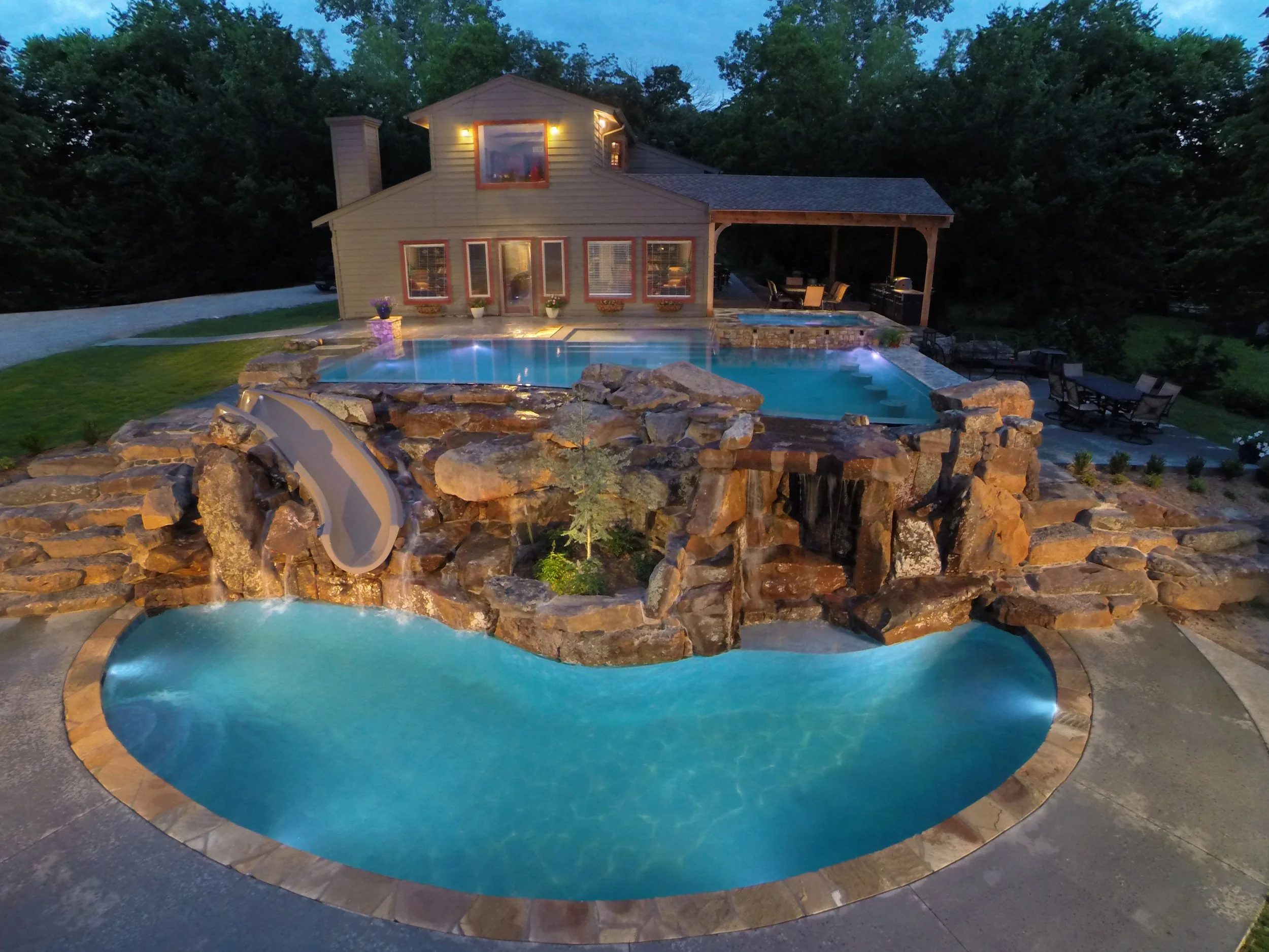 This custom resort-style pool project was designed as a complete backyard destination, combining luxury entertaining spaces with family-friendly features. The upper adult pool includes a vanishing edge and perimeter overflow detail, creating a clean,