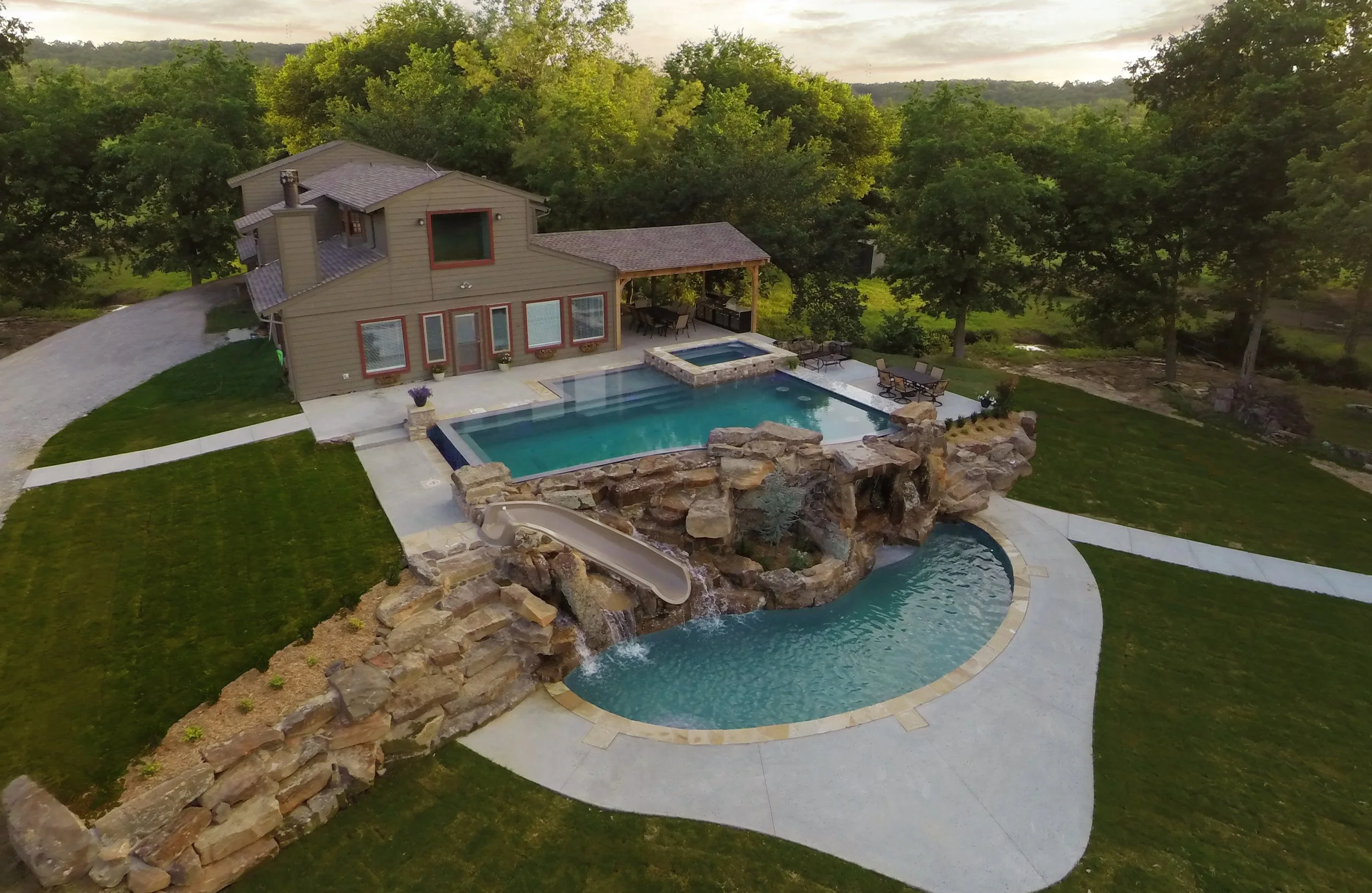 This custom resort-style pool project was designed as a complete backyard destination, combining luxury entertaining spaces with family-friendly features. The upper adult pool includes a vanishing edge and perimeter overflow detail, creating a clean,