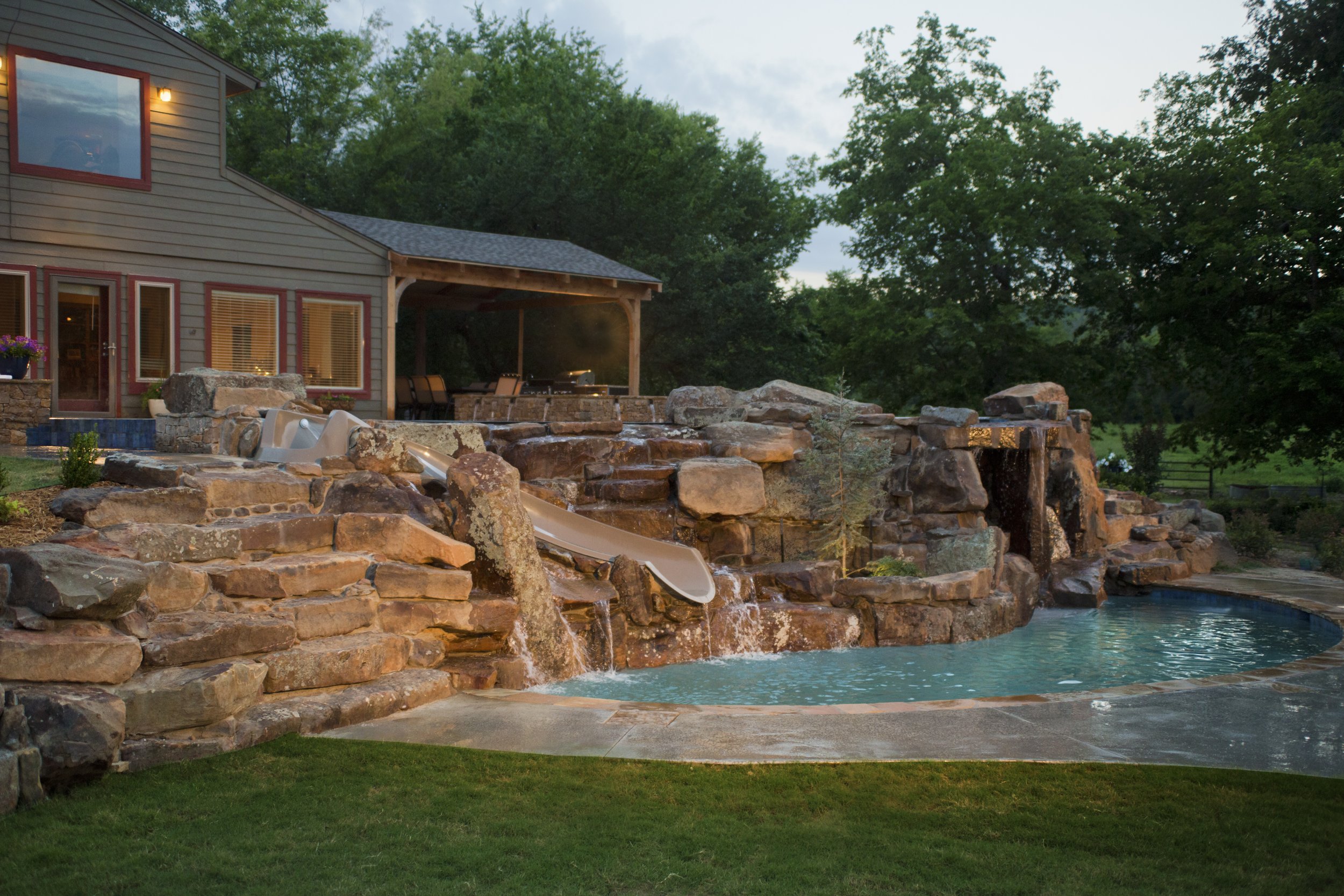 This custom resort-style pool project was designed as a complete backyard destination, combining luxury entertaining spaces with family-friendly features. The upper adult pool includes a vanishing edge and perimeter overflow detail, creating a clean,