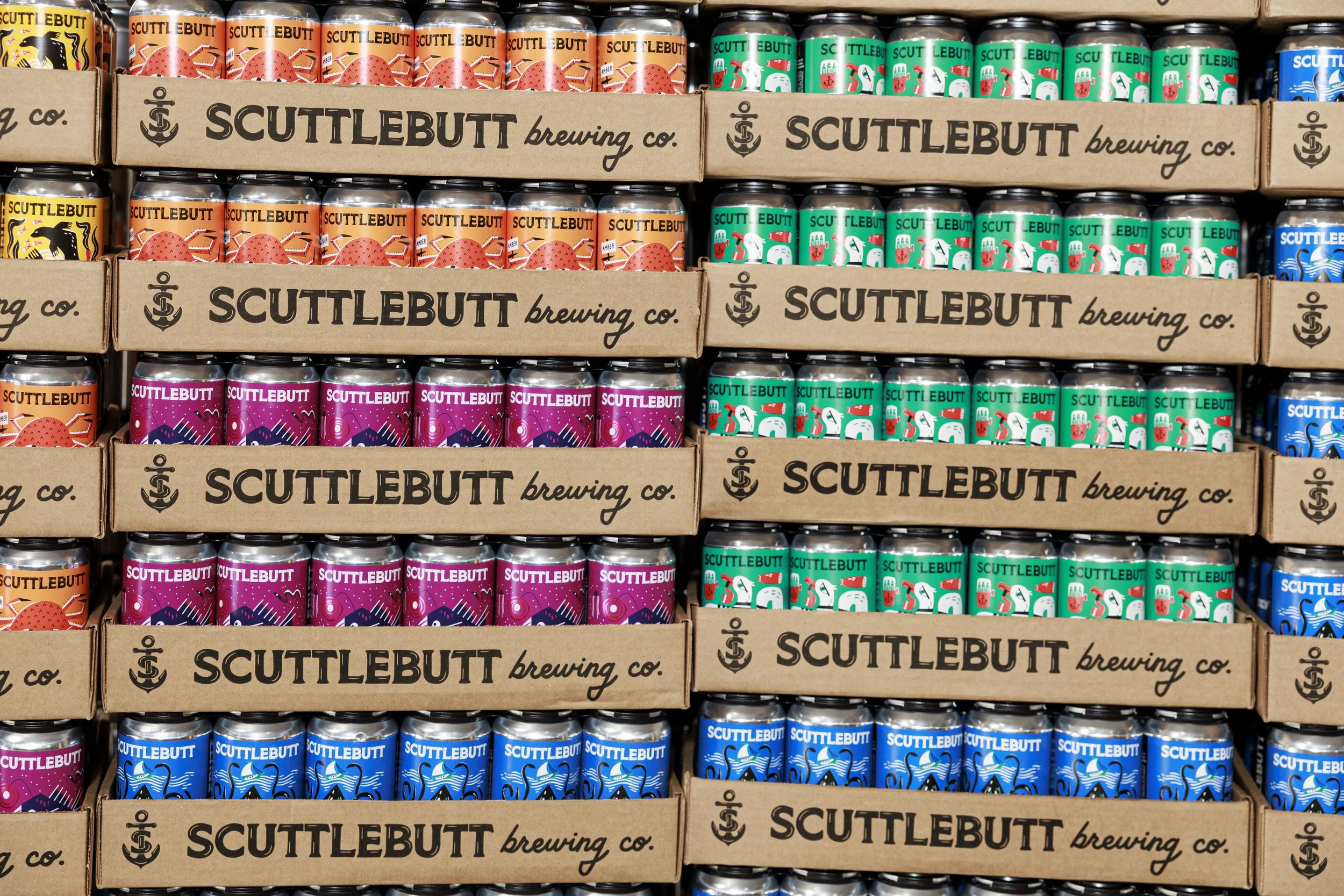 Rows of colorful cans of Suttlebutt Brewing Co. beers on store shelves, with boxes displaying the brewery's logo and name.