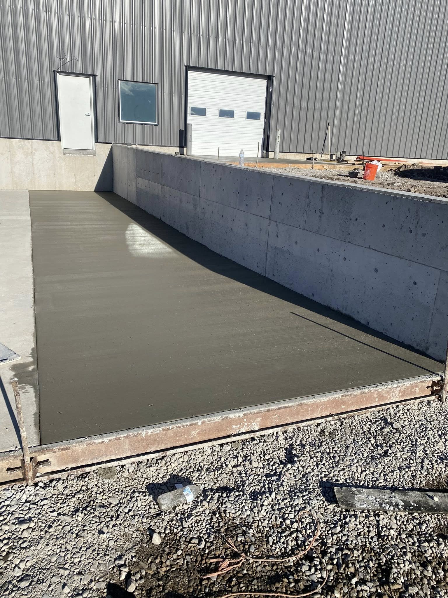 Freshly poured concrete slab with a straight edge, surrounded by gravel.