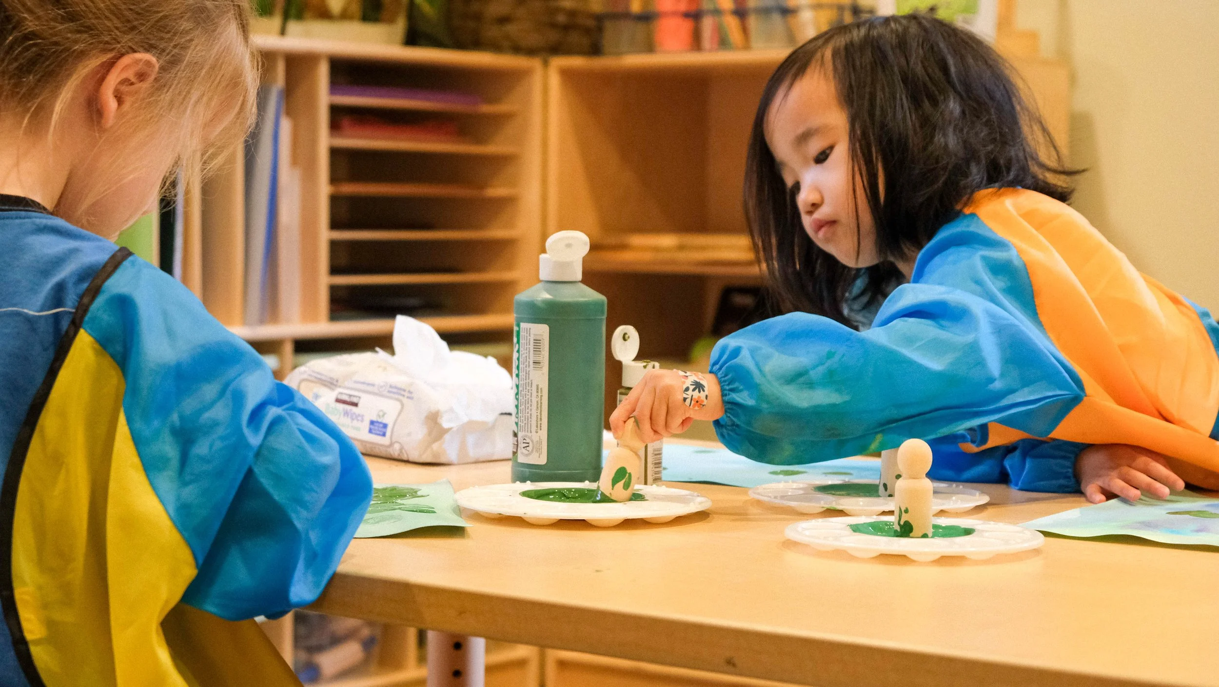 Childern at Global Early Learning in Bellevue, Washington doing arts and crafts - painting and decorating at a table in our classroom.