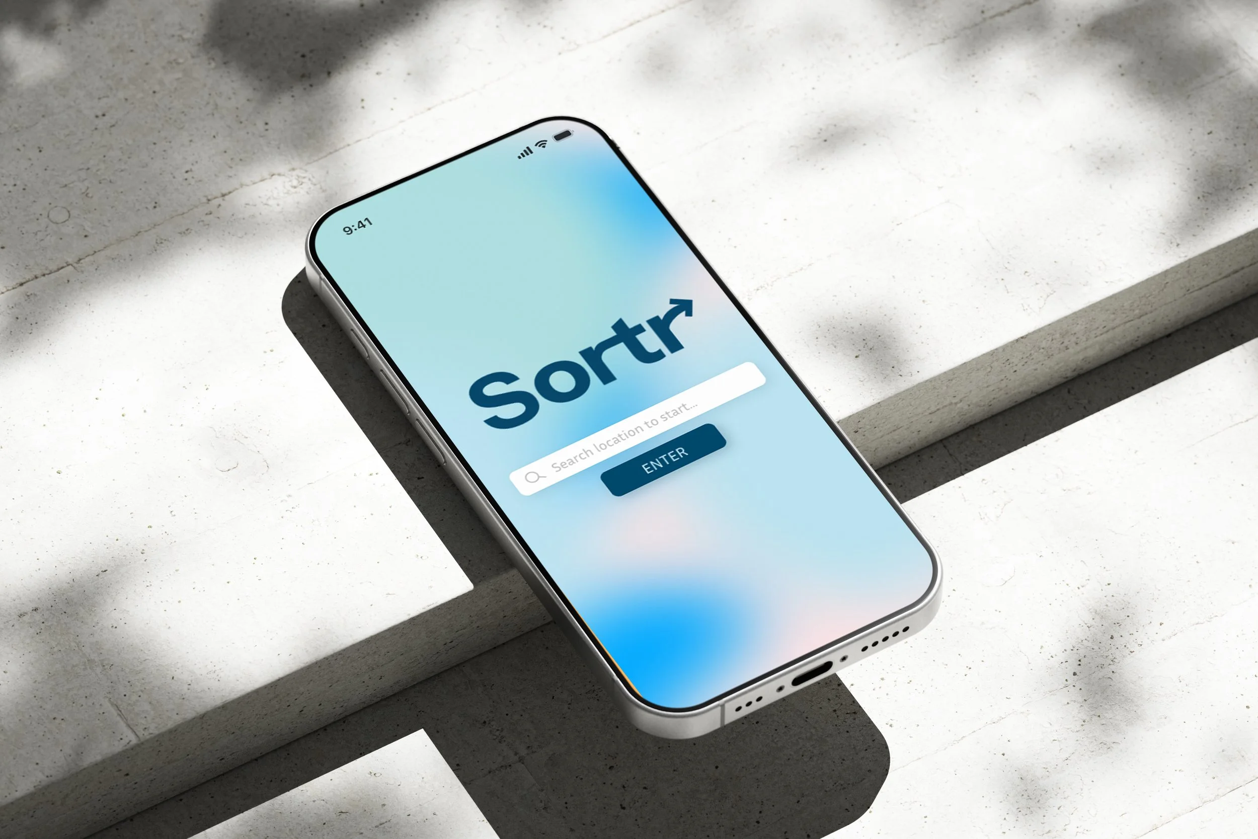 A smartphone displaying a sorting app with a search bar and an 'Enter' button placed on a concrete surface.