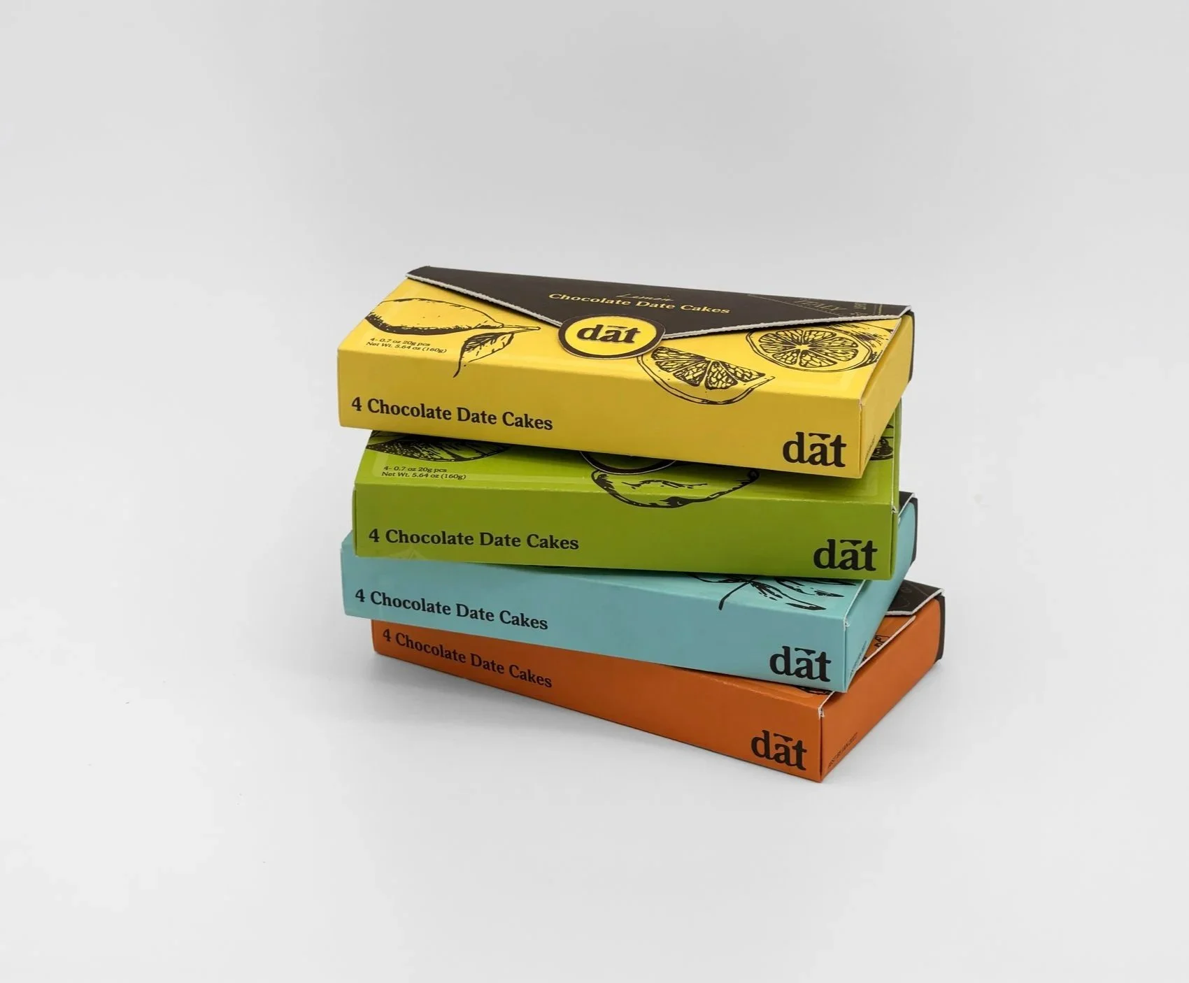 Stack of four colorful boxes of dark chocolate date cakes, arranged in a pyramid, with each box in green, blue, orange, and yellow, on a plain white background.