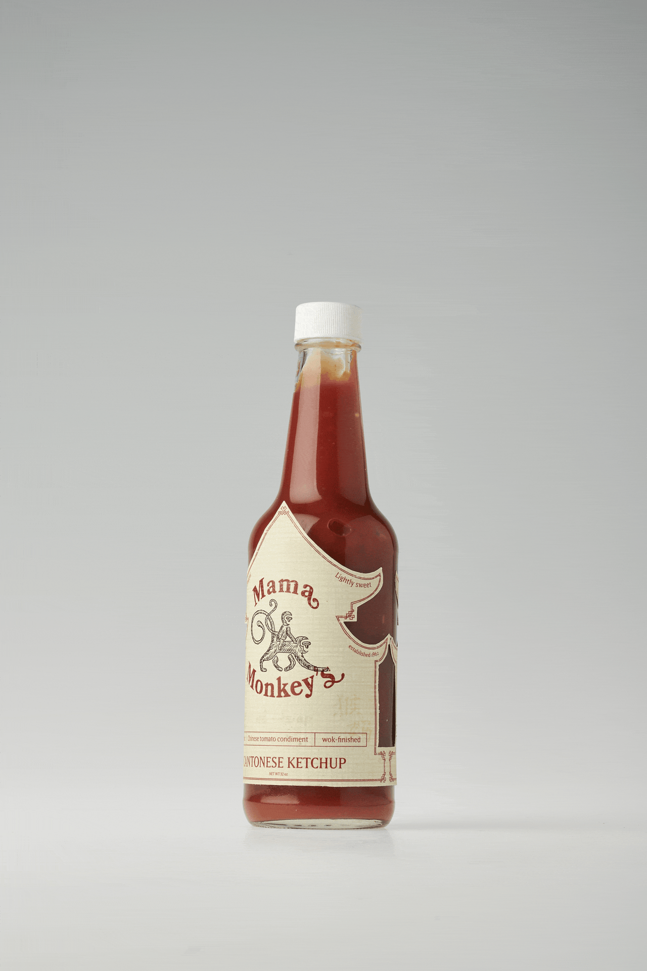 A bottle of Mama Monkey's Cantonese Ketchup with a white cap, standing upright on a white surface against a plain background.