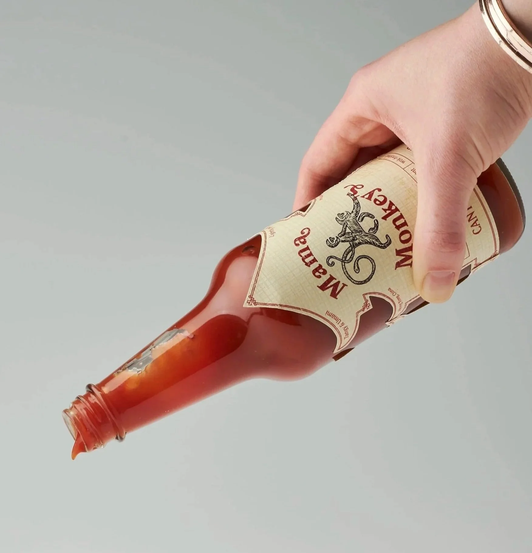 A hand holding a Molson Canadian beer bottle at an angle with some beer spilling out.