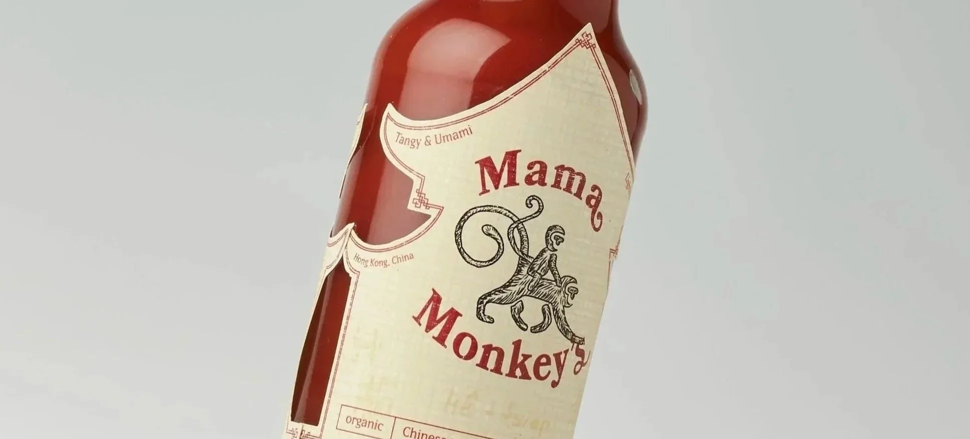 A bottle of Mama Monkey hot sauce with a beige label featuring a drawing of a monkey and red text, indicating it is made in Hong Kong, China.
