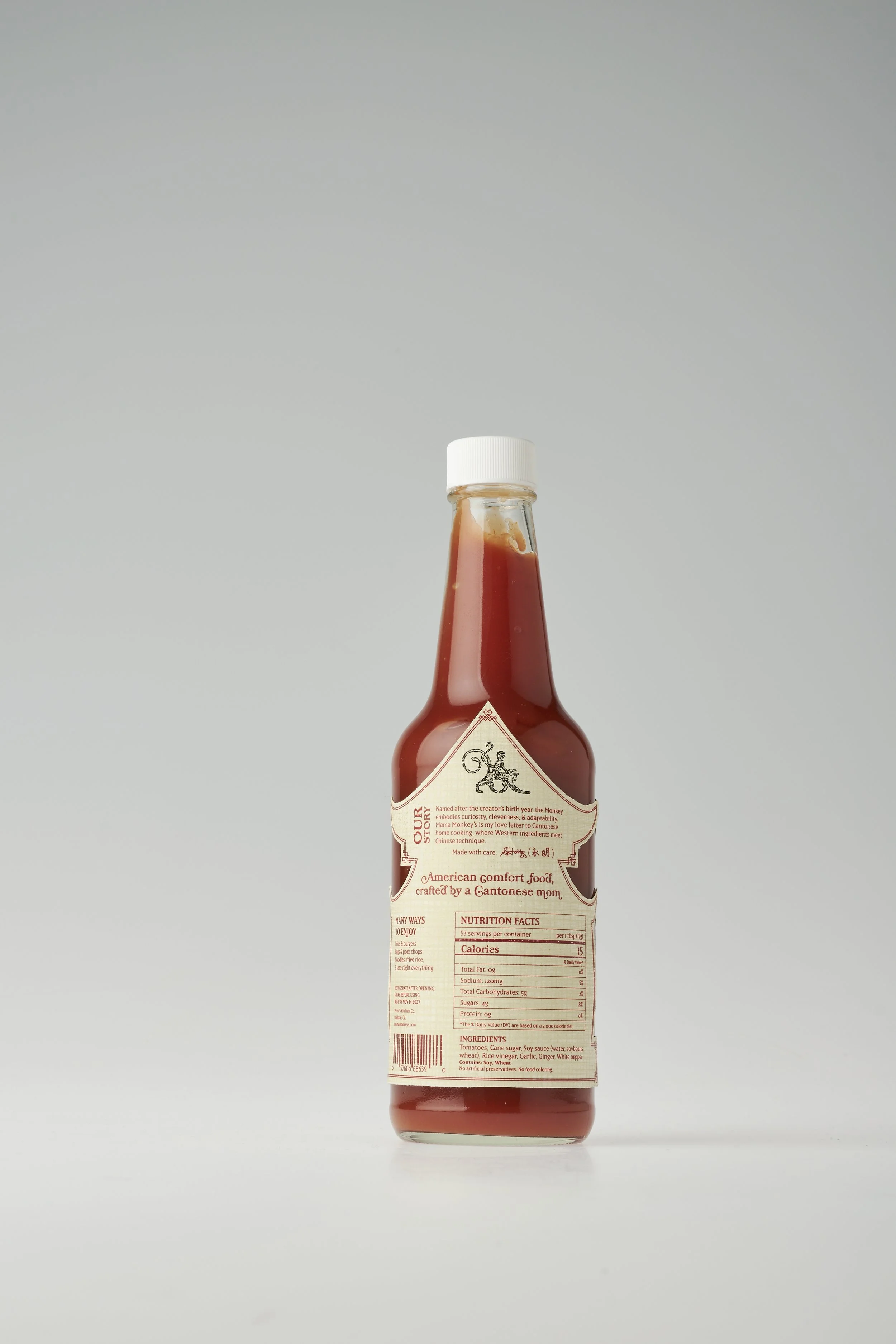 Bottle of ketchup with a white cap on a plain light background.