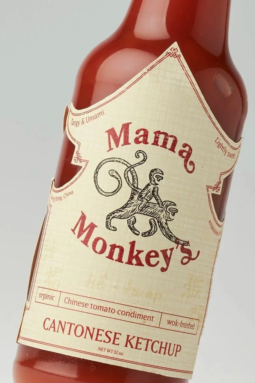 A bottle of Mama Monkey's Cantonese Ketchup with a label featuring a monkey illustration, and text indicating it is organic, lightly sweet, wok-finished, Chinese tomato condiment, 32 ounces.