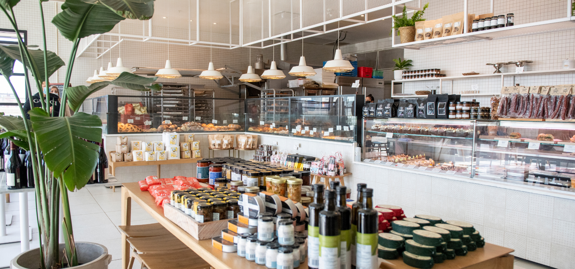 Comptoir d'épicerie fine avec sélection de produits fins et plantes vertes.