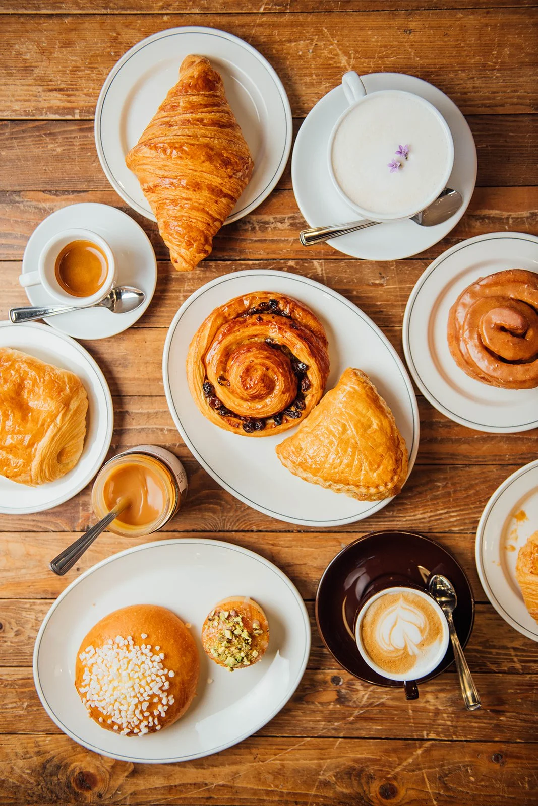 Viennoiseries, café espresso et pâtisseries fraîches servis sur une table.