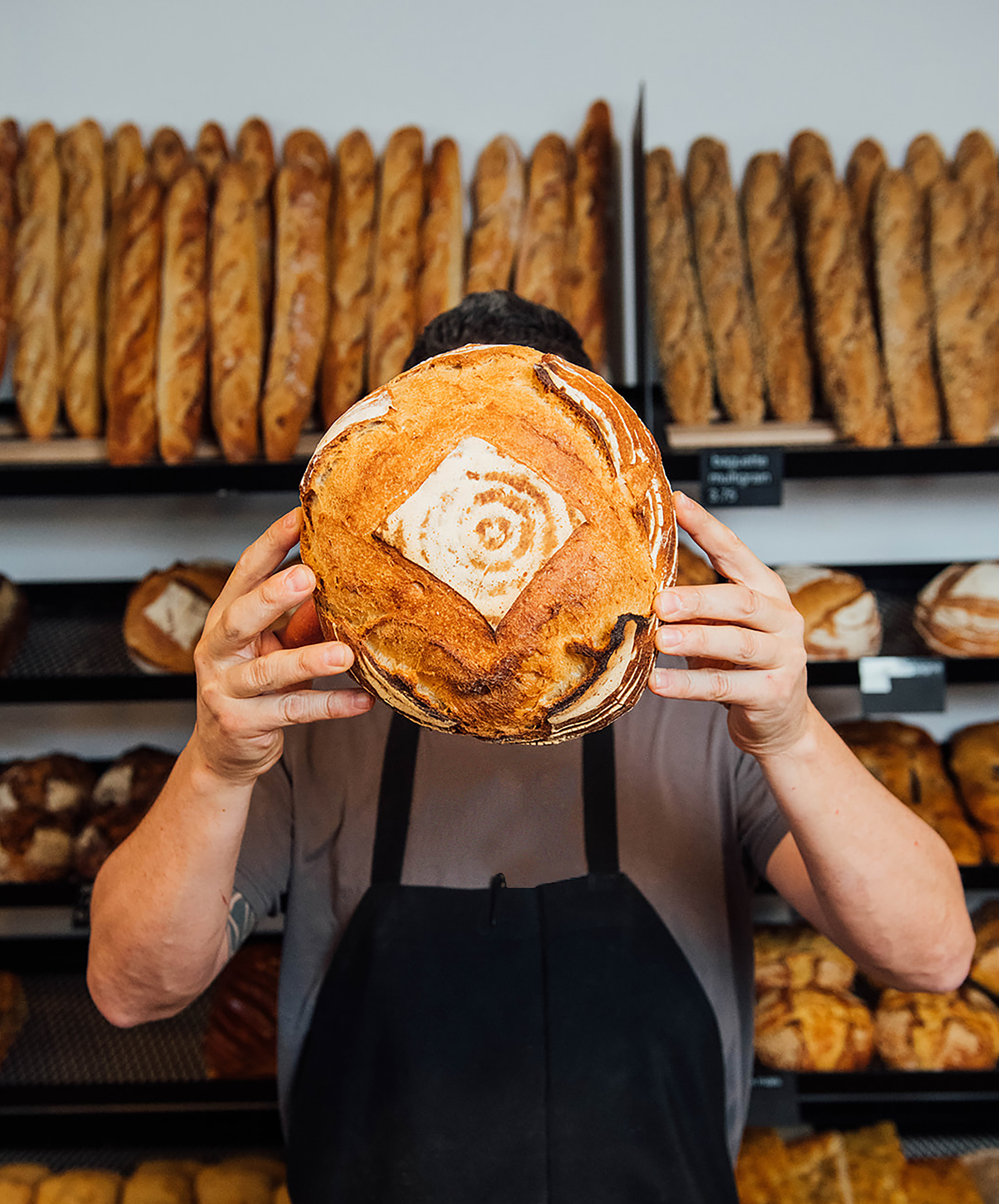 Boulanger tenant fièrement un pain rond fraîchement cuit.