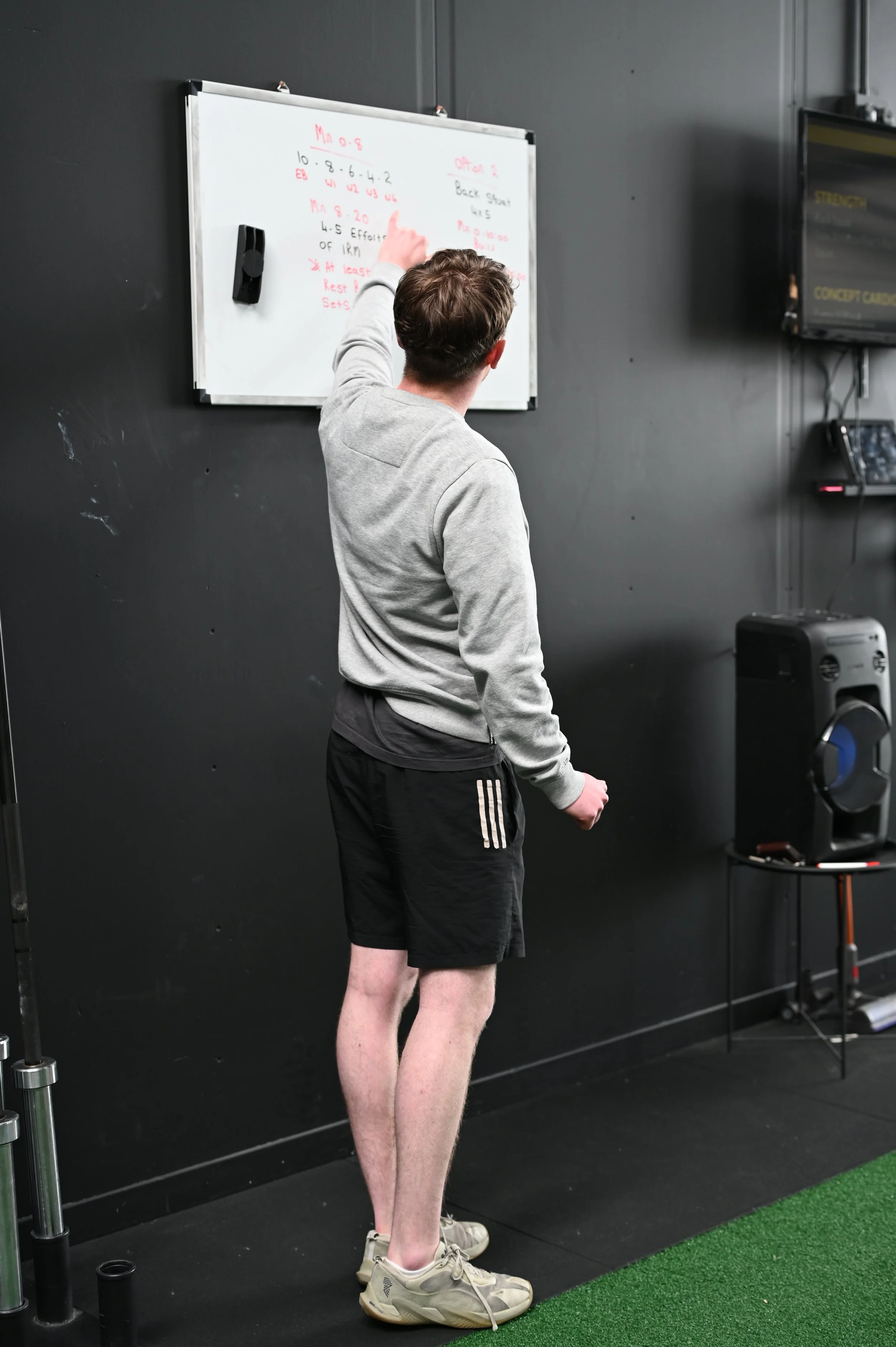 Coach reviewing programming on a whiteboard during a personal training session at Alliance Training Club