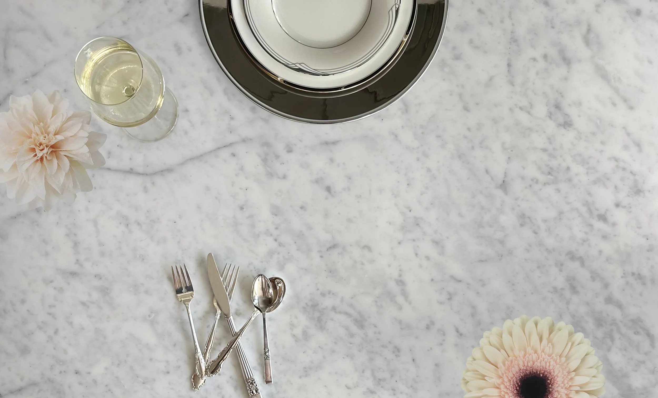 Marble table with curated (mixed and matched) dinner, salad, and bread and butter plates. Pictured plate settings are: Argenta and Bouquet. Silverware set: Sterling.