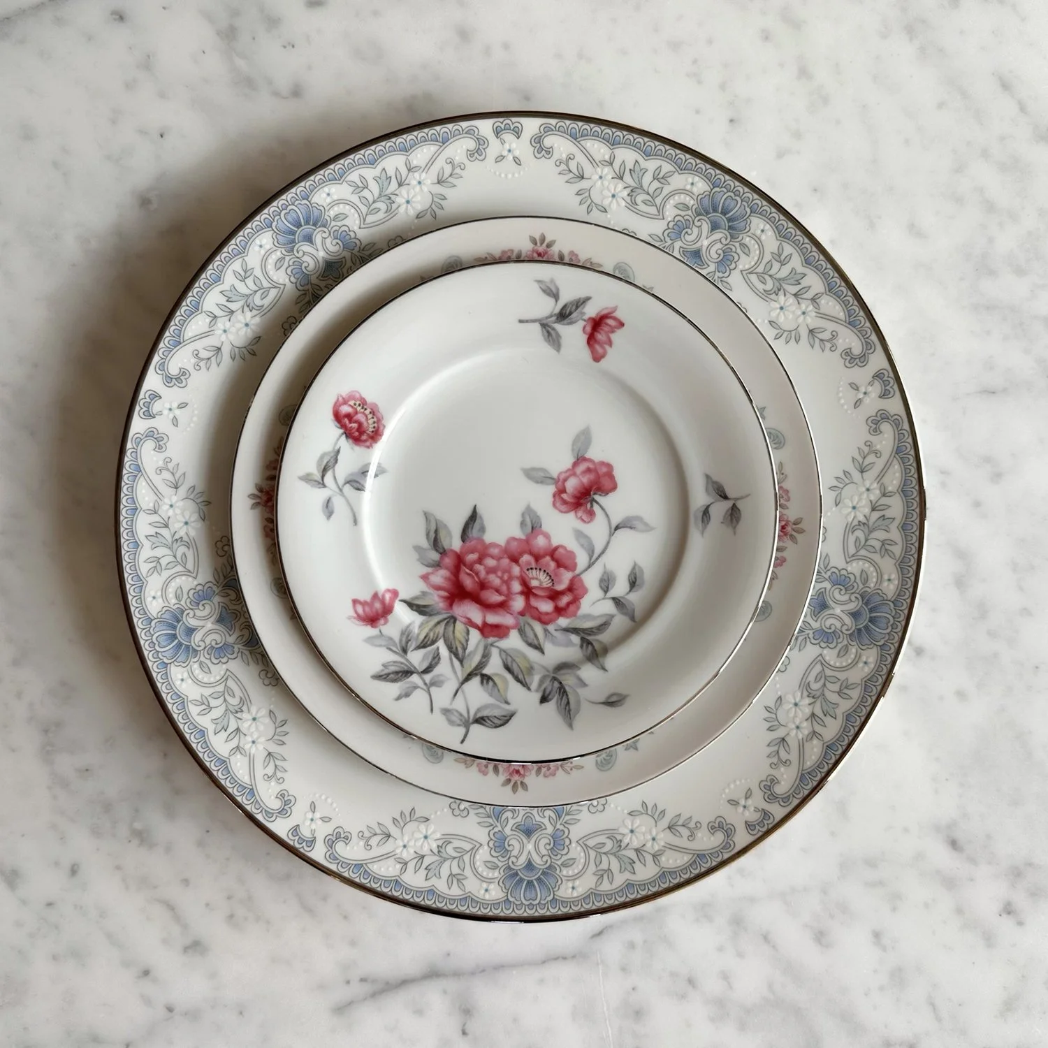 Design forward, sustainable, mixed and matched vintage plate setting featuring roses. Rent Bouquet for your wedding for a luxuriously elevated look.