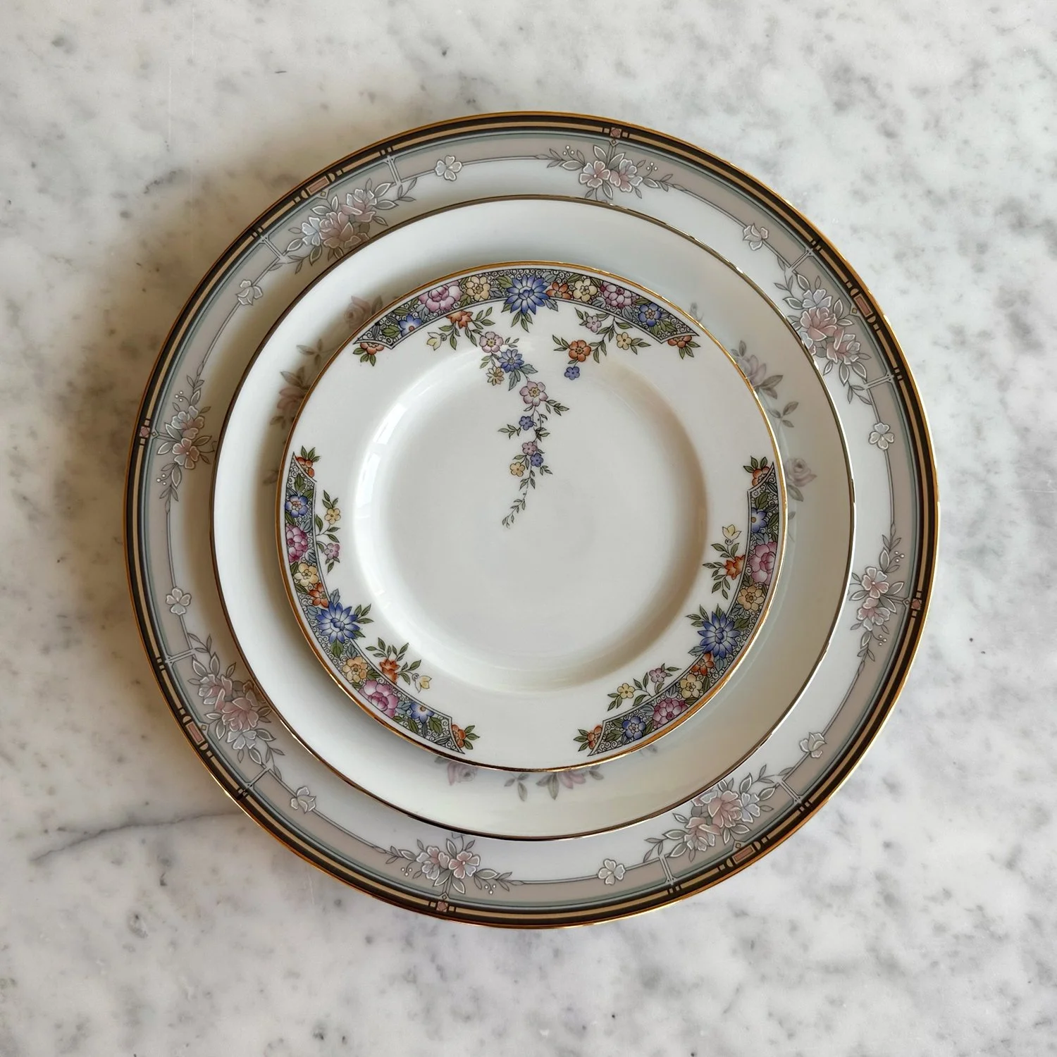 Close up of Bouquet Collection 3 plate setting featuring floral vintage, mismatched china. Mixed matched pastel themed dinner, salad, and bread and butter plate.
