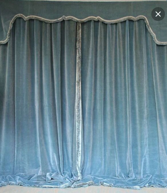 Blue velvet curtain with decorative trim at the top and bottom.