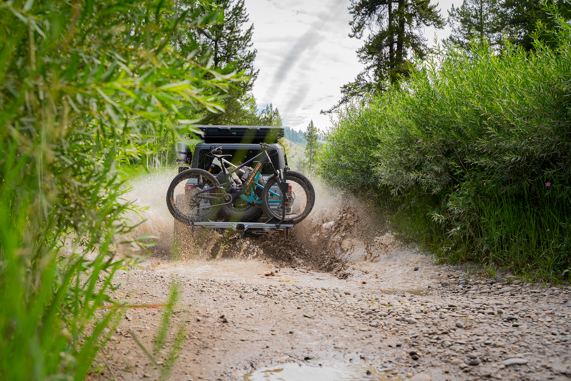 ford bronco with bikes on the back splashing through the mud
