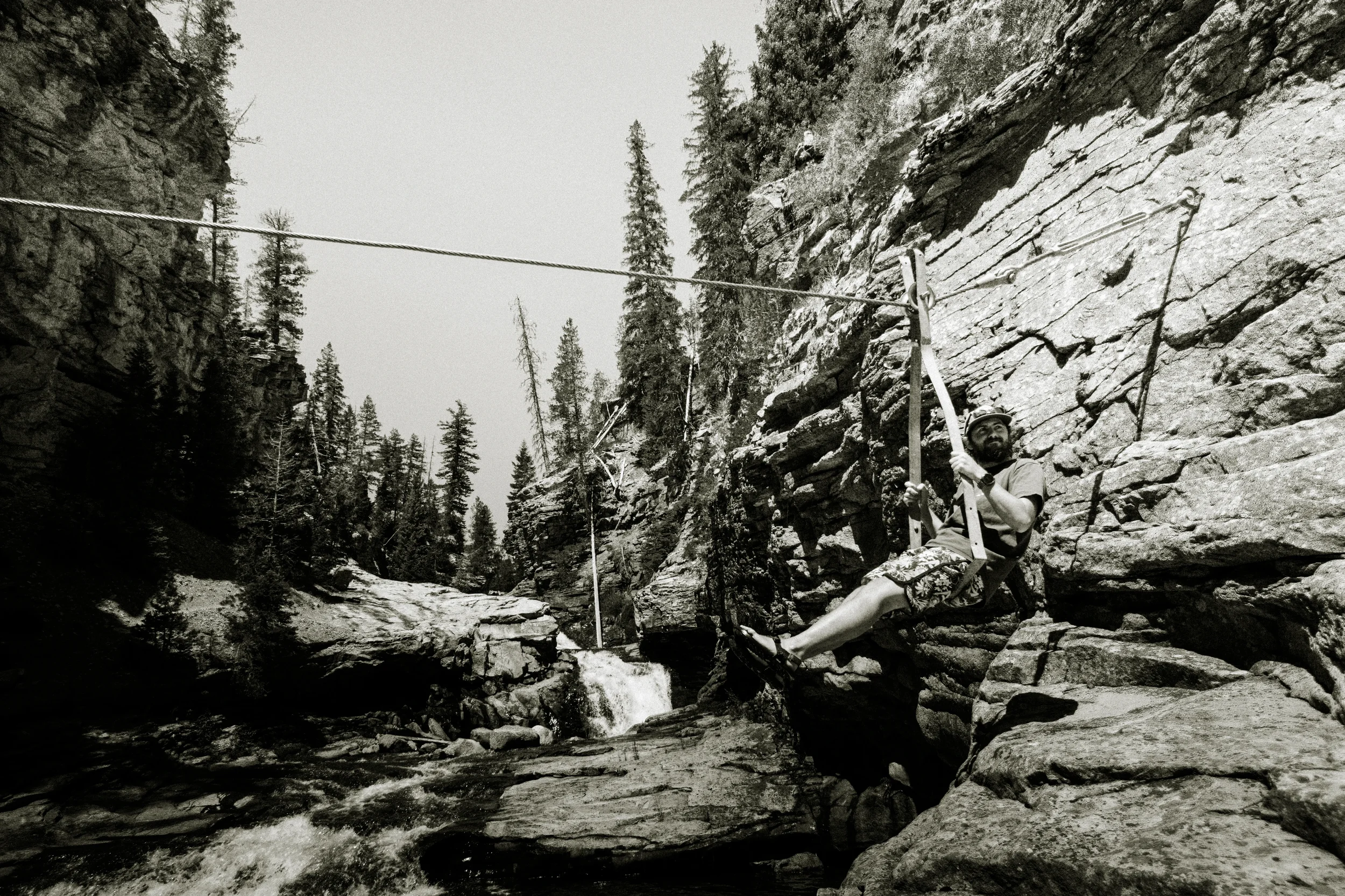 man sitting an a cable pulley system above a river