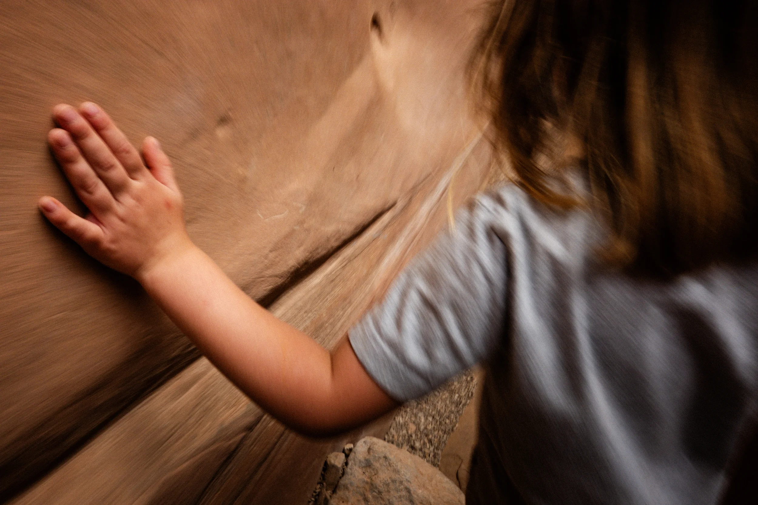 child dragging hand on sandstone canyon wall