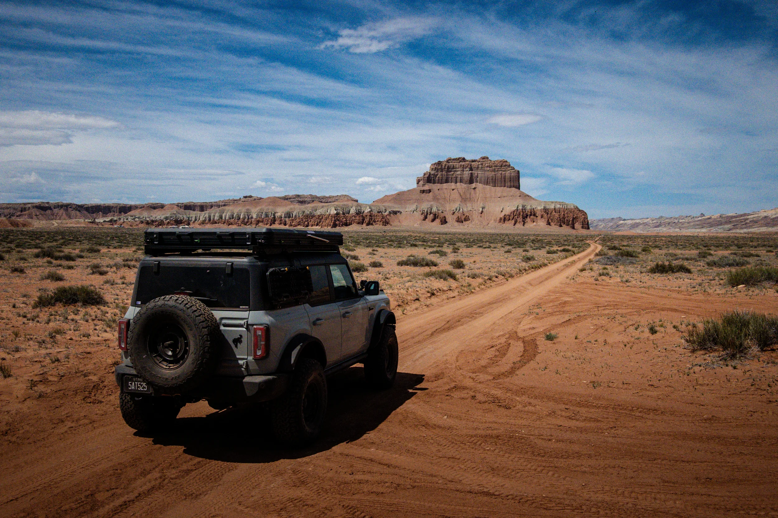 ford bronco driving down dirt road in the desert